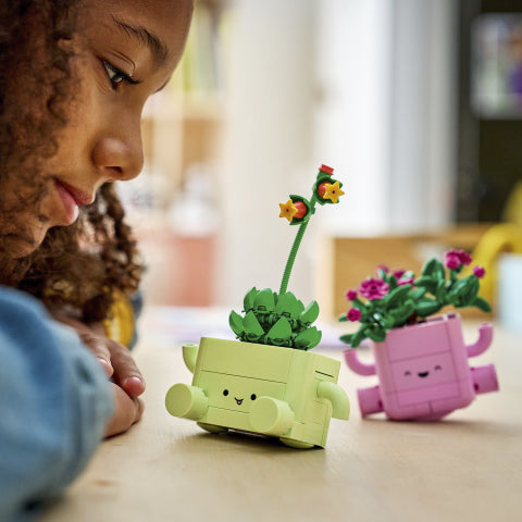 Barn ser på LEGO blomster i gule og rosa potter med ansikter