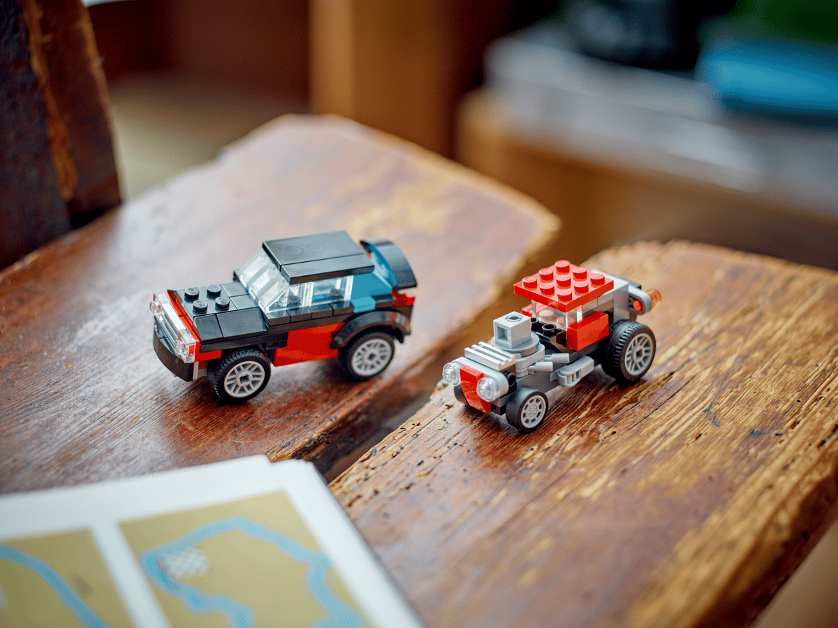 To LEGO-biler på trebord – rød og blå bil med detaljerte hjul og karosseri