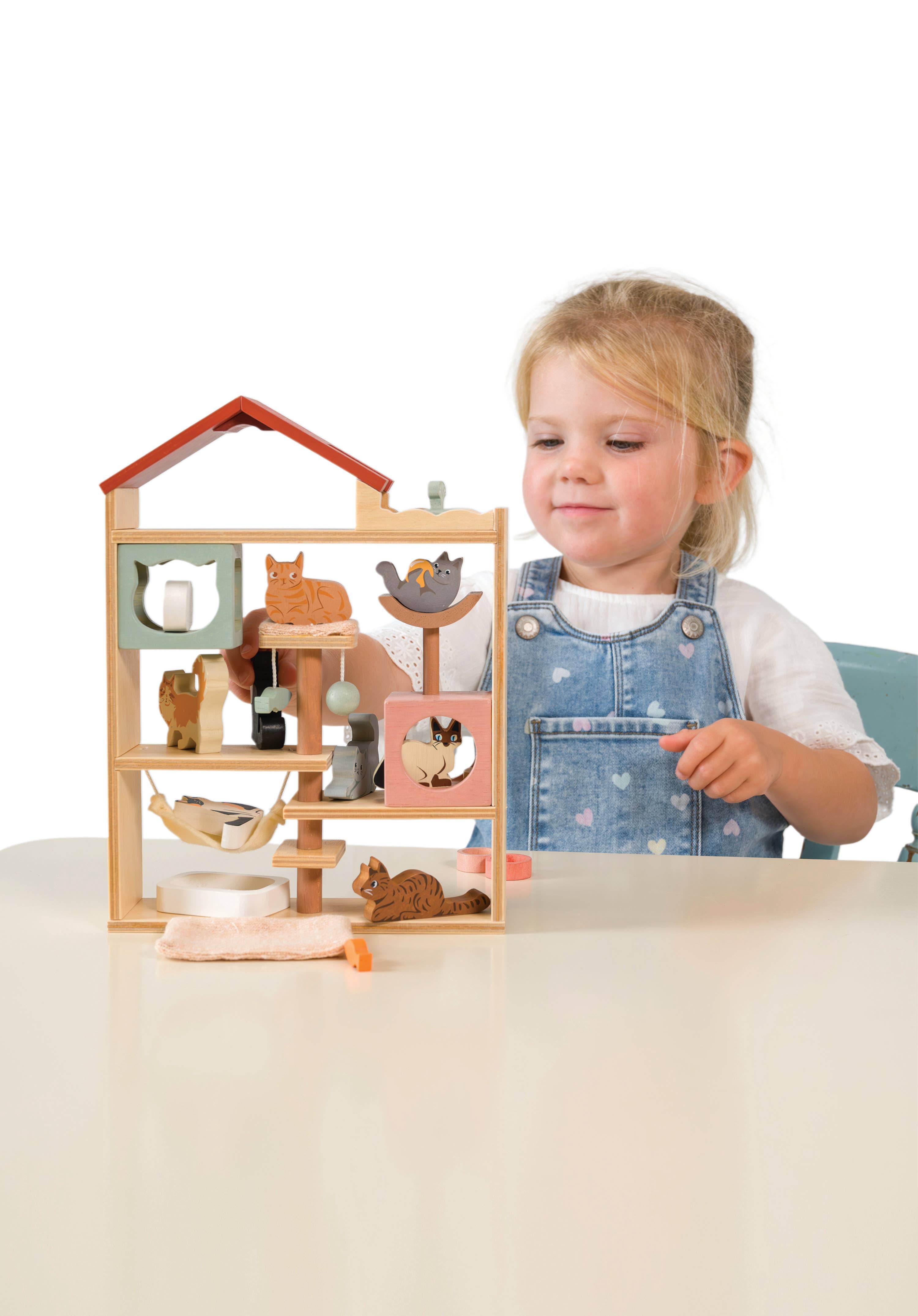 Liten jente leker med tre lekehus med katter, perfekt barnelek for fantasispill og utvikling